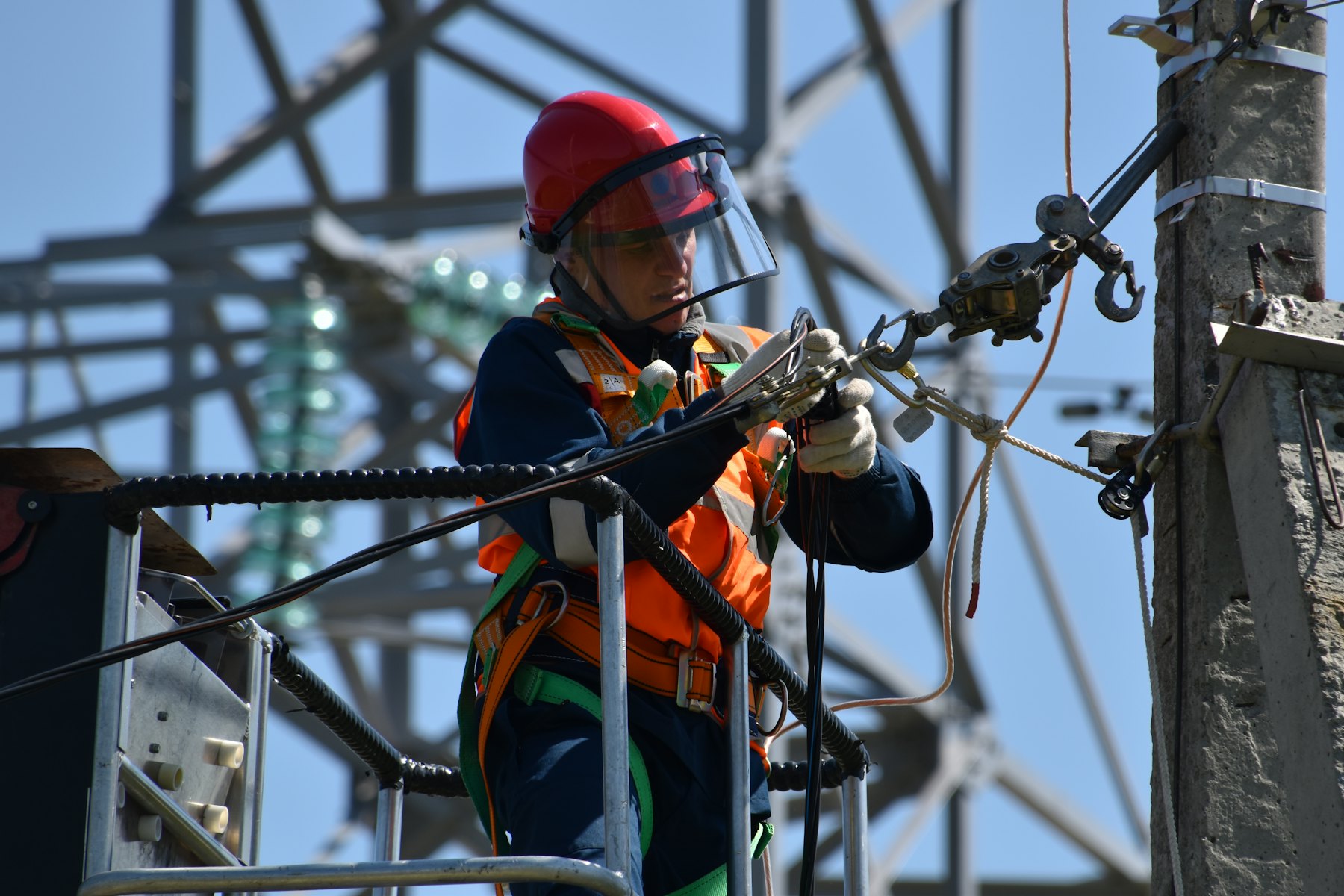 Técnico con casco y careta de protección trabajando en una red de alta tensión